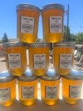 Jars of Taylor Orange Blossom raw Honey stacked outdoors with a clear sky.