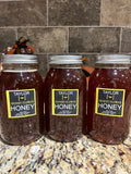 Three jars of  locally harvested Desert Flower raw Honey on a granite countertop with a tiled backsplash.