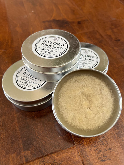 Three tins of Taylor's Boot Love on a wooden surface.