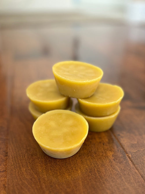 Yellow raw beeswax melts stacked on a wooden surface in St. George Utah